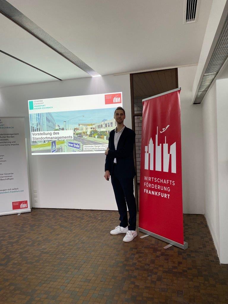 Mann neben einem roten Banner mit dem Text Wirtschaftsförderung Frankfurt