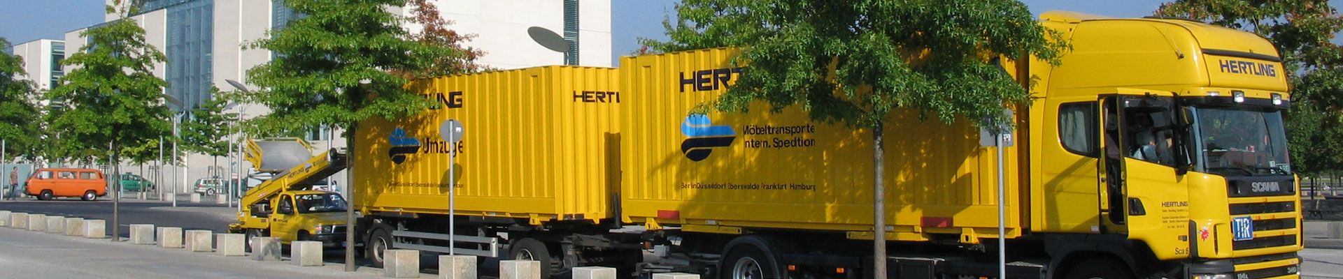 HERTLING Umzugstransporter mit Anhänger vor einem HERTLING Lastenaufzug PKW