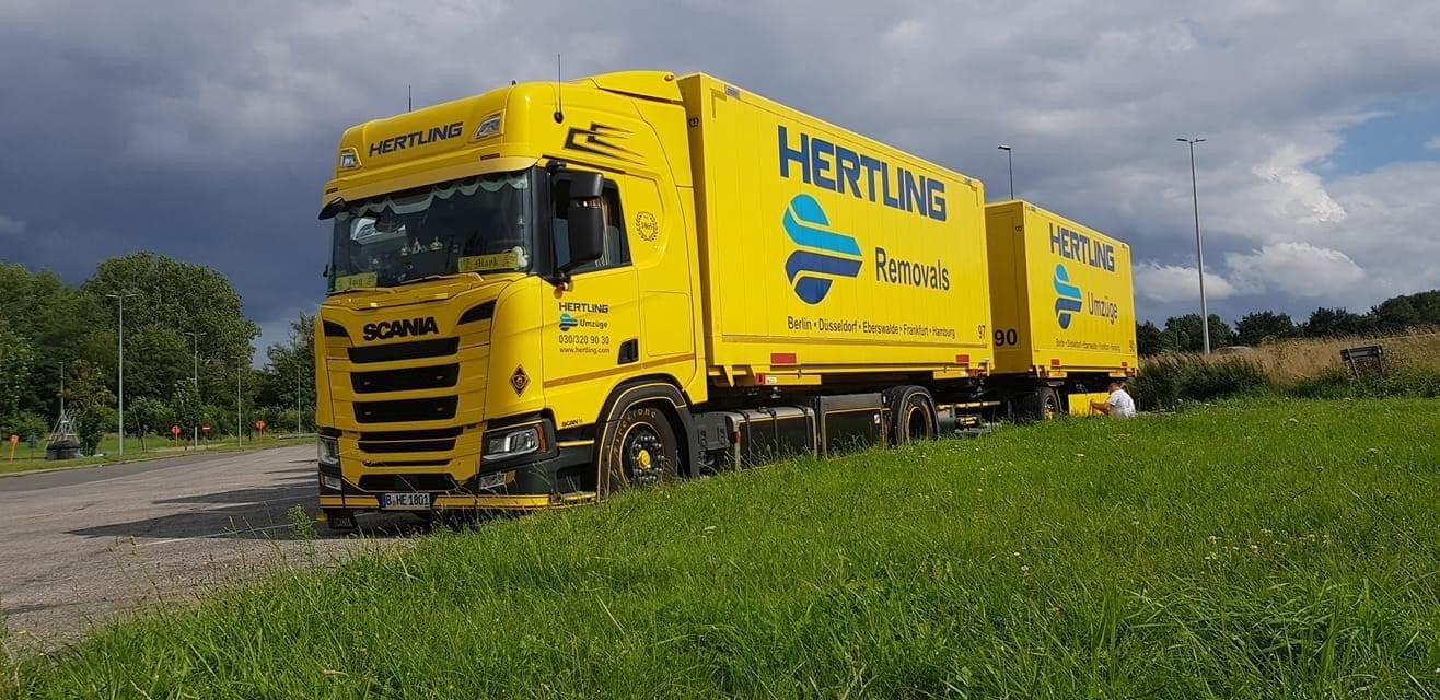 HERTLING model world truck with trailer in a landscape from the front left