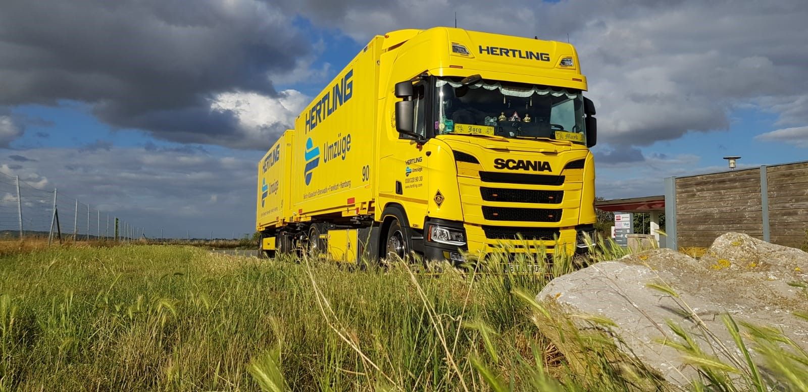 HERTLING model world truck with trailer in a landscape from the front